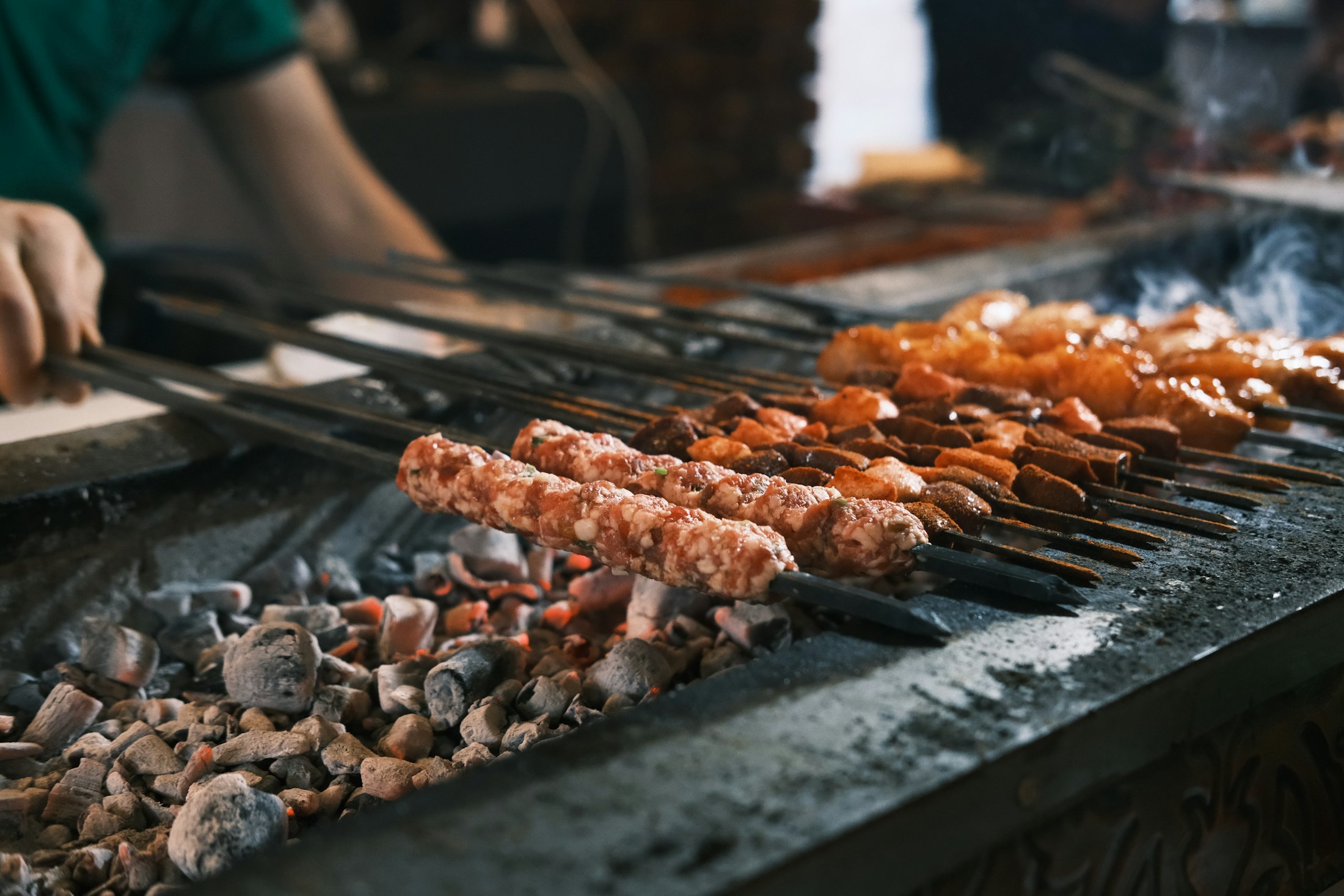 Adana kebab skewers grilling over charcoal at the ocakbaşı counter